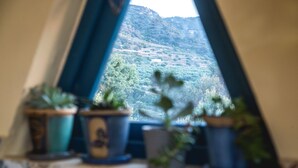 A window view of a mountainous landscape with potted plants on a windowsill. - Luxurious villa, idyllic view, 5km from town & beach, total privacy, large pool (Rethimno)