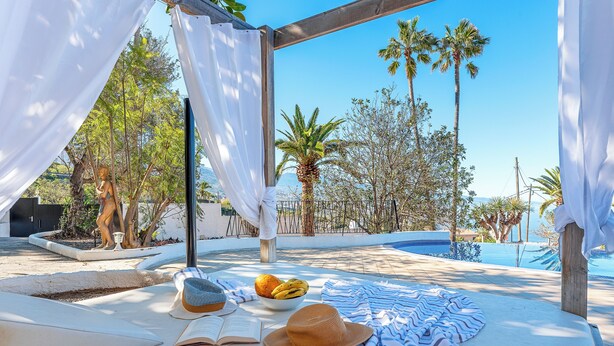 A poolside area with a covered seating area, a hat, a bowl of fruit, and an open book. - Private Garden & pool, Sea View, near restaurant, free Wi-fi, 5,5 km from Beach (La Matanza de Acentejo)