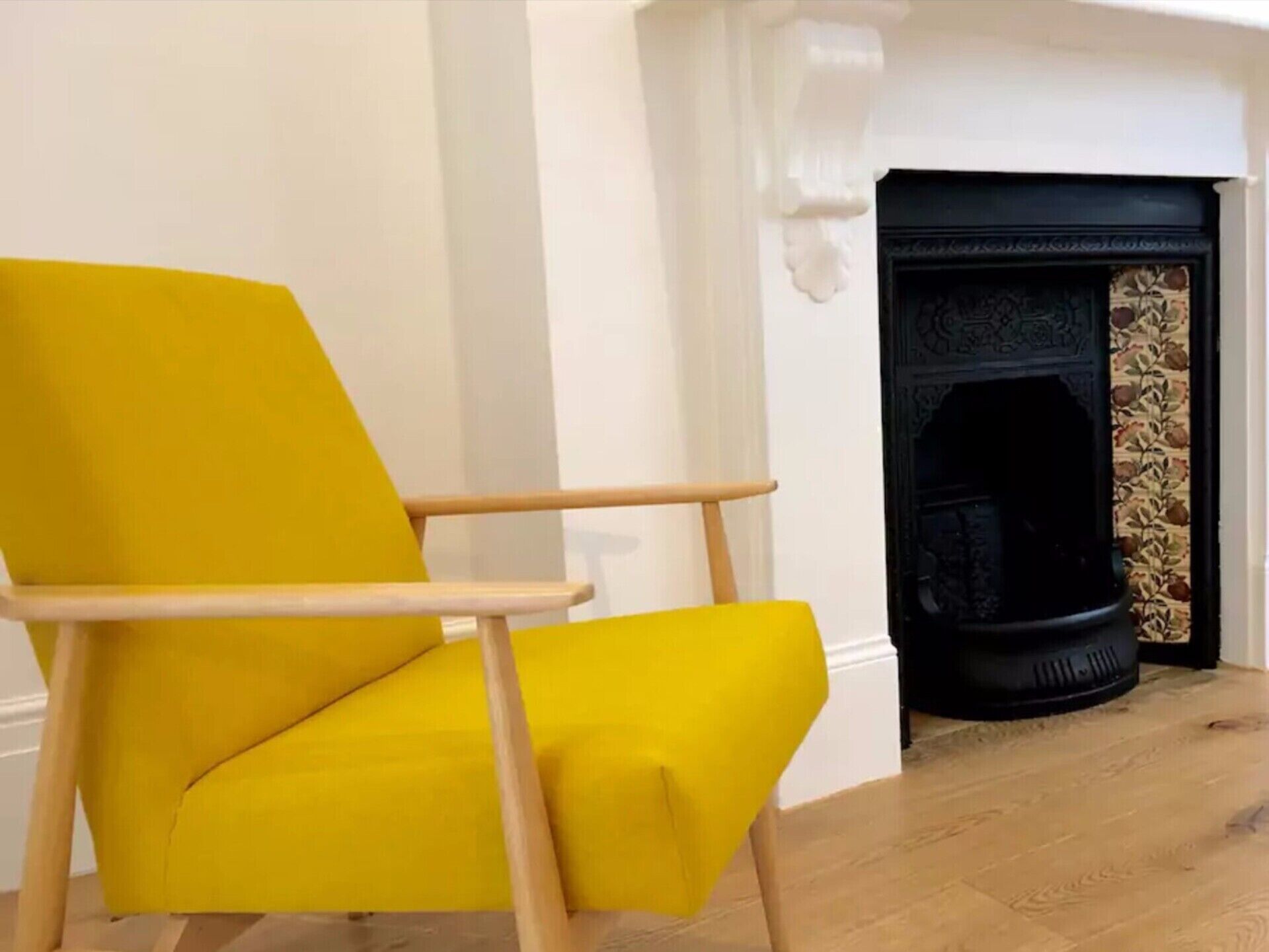 Un sillón amarillo en una habitación con chimenea.