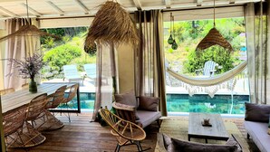 A spacious outdoor seating area with wicker furniture, a hammock, and a view of a swimming pool. - Local stone Provencal country cottage with pool  (Saint-André-De-Roquepertuis)
