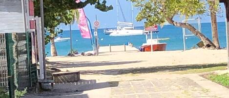Ein gepflasterter Weg führt zu einer Uferpromenade, im Hintergrund liegt ein Boot angedockt.