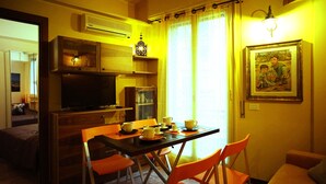 A dining area with a table set for four, a television, and a painting on the wall.