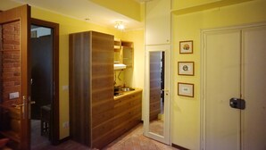 A narrow hallway with a wooden cabinet, a sink, and a door leading to another room.