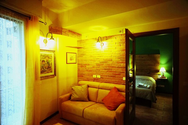 Una habitación acogedora con pared de ladrillo, un sofá y una cama.