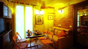 A cozy dining area with a table set for four, a sofa, and a brick wall.