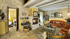 Ein gemütliches Wohnzimmer mit Steinwand, Kamin, einer Couch und einem Bücherregal.