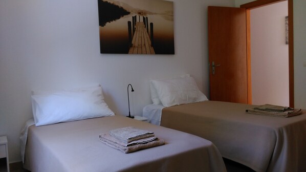 Una habitación de hotel con dos camas, una puerta de madera y un cuadro de un puente en la pared.