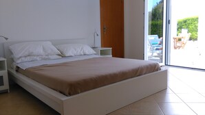 Un dormitorio moderno con cama, mesitas de noche y vistas al exterior.