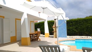 Un espacio al aire libre cubierto con piscina, una mesa y sillas, y una estructura de piedra.