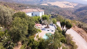 Un bâtiment blanc, doté d’un toit en tuiles, entouré d’une végétation luxuriante et agrémenté d’une piscine.