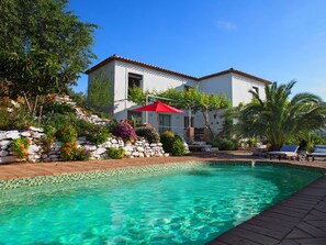 Una piscina con agua cristalina, rodeada de un muro de piedra y abundante vegetación.