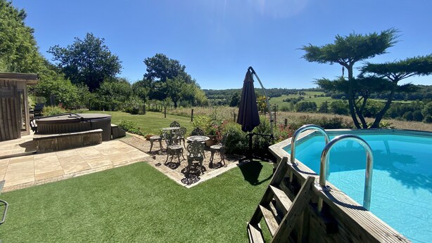 Un patio trasero con piscina, una terraza de madera y un área de patio con mobiliario exterior.