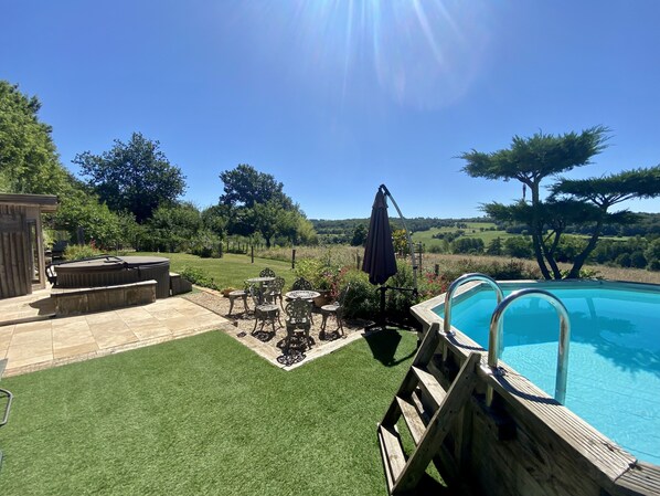 Un patio trasero con piscina, una terraza de madera y un área de patio con mobiliario exterior.