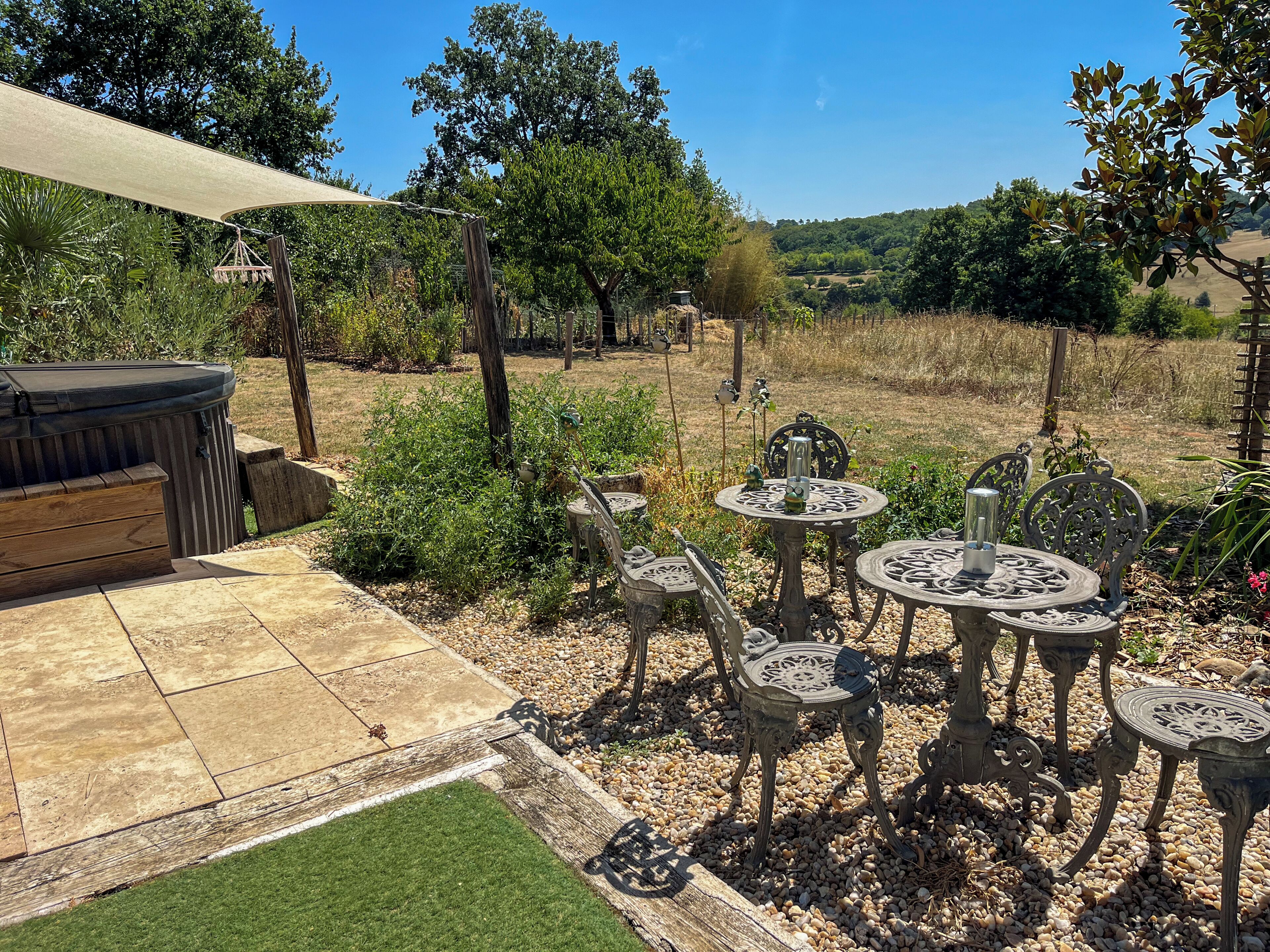 Une terrasse avec mobilier d’extérieur, un jacuzzi et un espace jardin.