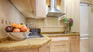 A kitchen with a granite countertop, a stainless steel sink, a built-in oven, and a white refrigerator.
