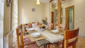 A dining area with a table set for four, a sofa, and a radiator.