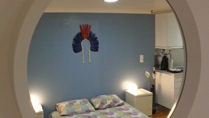 A bedroom with a bed, pillows, a nightstand, a mirror, and a wall decoration. - Best in Alfama - Free pick up (Lisboa - Alfama)