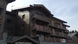Ein mehrgeschossiges Gebäude mit einer Stein-Fassade und hölzernen Balkonen. Im Erdgeschoss ist die Beschilderung 