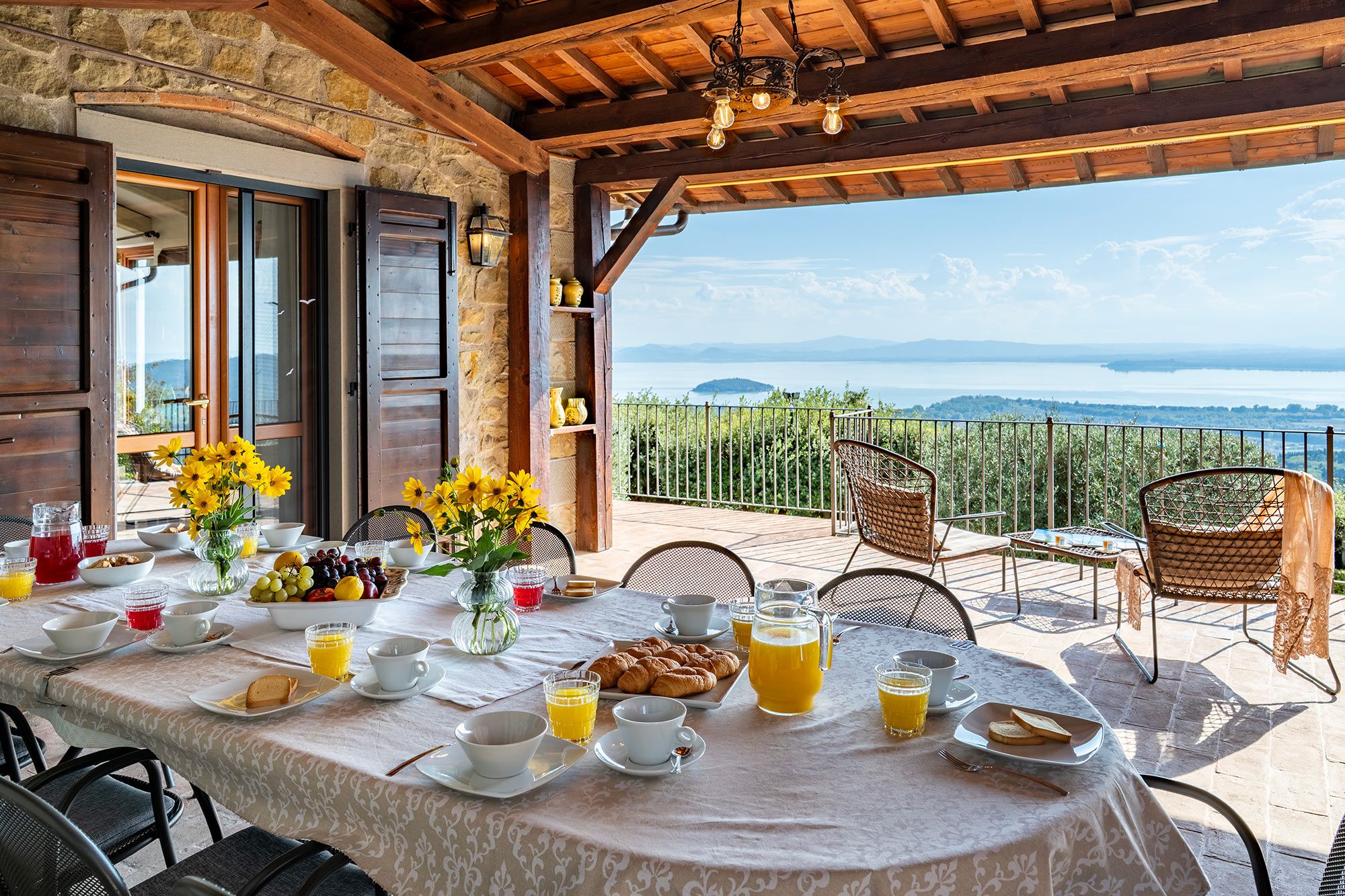 A breakfast table set with various dishes and drinks, overlooking a scenic view.