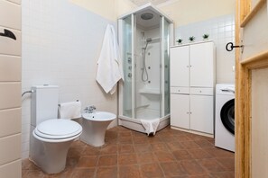 Een moderne badkamer met toilet, bidet, douche en wasmachine.