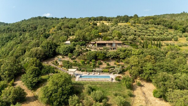 A villa with a swimming pool surrounded by lush greenery and hills.