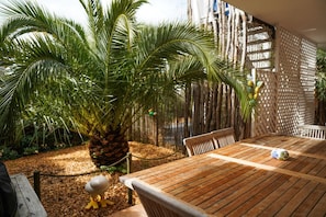 Une table en bois avec des chaises, une plante décorative et une clôture en treillis, le tout dans un cadre de jardin.