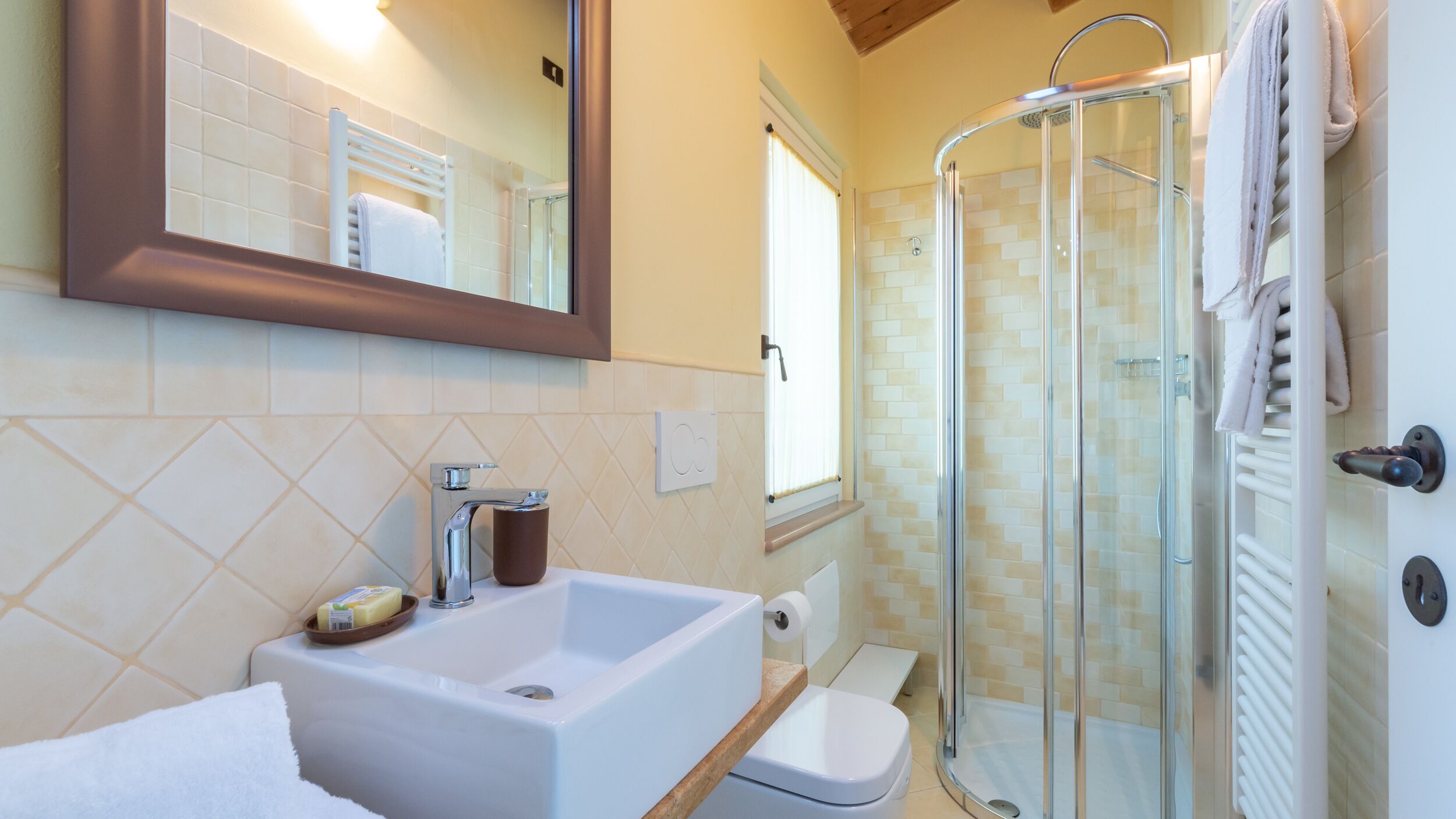 A bathroom with a sink, mirror, towel rack, shower, and toilet.