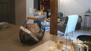 A kitchen counter with a coffee maker, a candle, and a basket. There is a wooden post in the center of the room.