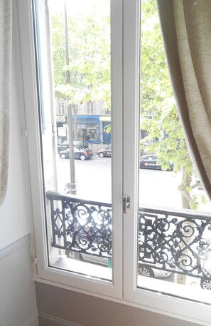 A window with a view of a street and parked cars outside. - Modern apartment near the Champs Elysées and the Palais des Congrès (Paris)