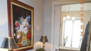 A hallway with a console table, two lamps, a vase, and a potted plant.