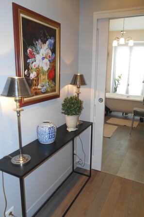 A hallway with a console table, two lamps, a vase, and a potted plant. - Modern apartment near the Champs Elysées and the Palais des Congrès (Paris)