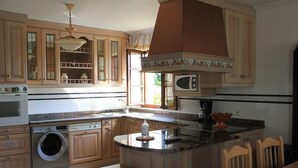 Una cocina con armarios de madera, lavadora integrada, microondas y una isla grande con taburetes.