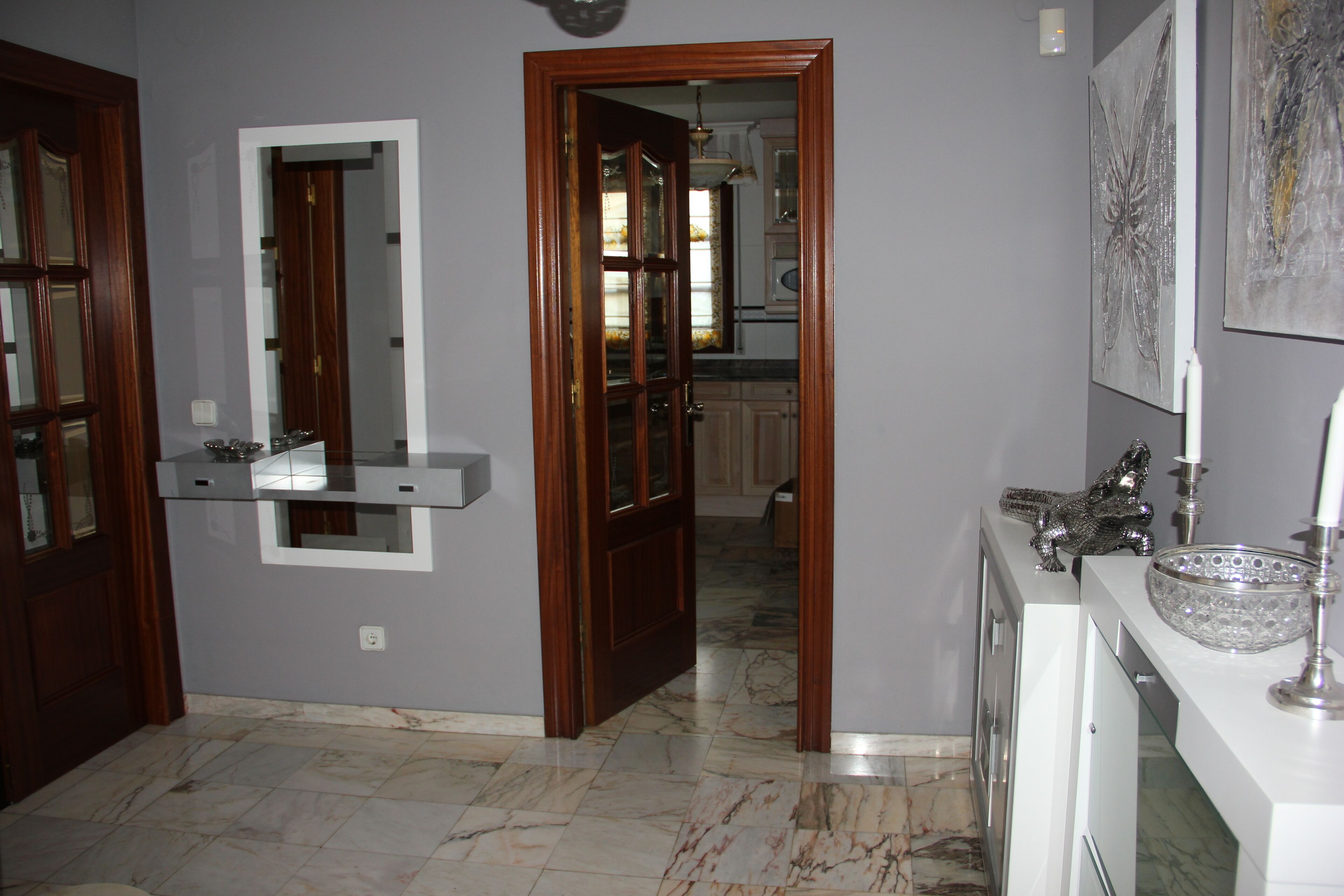 A modern kitchen with marble flooring, wooden cabinets, and a built-in oven.