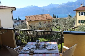 Ein Balkon mit Tisch für zwei Personen, mit Blick auf eine malerische Berg- und Seenlandschaft.