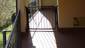 A corridor with a tiled floor leading to a gated entrance.