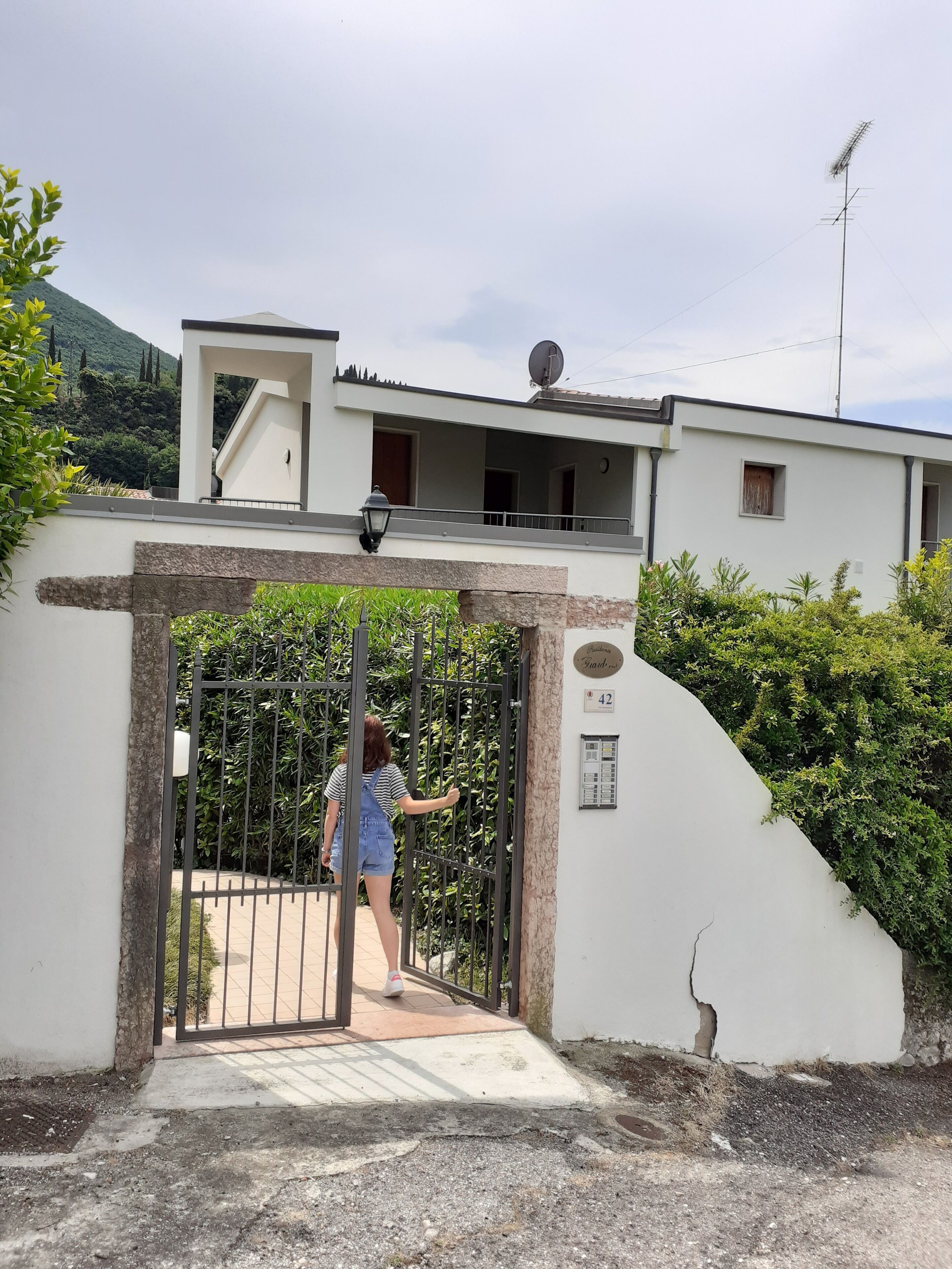 Ein begrenzter Zugang zu einem modernen Haus mit Satellitenschüssel, einem Balkon und Blick auf eine Berglandschaft.