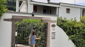 Ein begrenzter Zugang zu einem modernen Haus mit Satellitenschüssel, einem Balkon und Blick auf eine Berglandschaft.