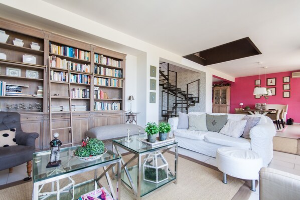 A modern living room with a large bookshelf, a glass coffee table, a white sofa, and a staircase leading to an upper level. - Villa between sea and mountain with private pool and sea view with private pool  (Capaci)