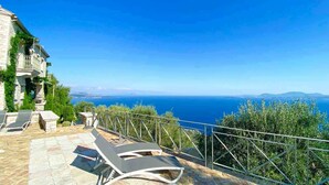 A stone building with a balcony overlooking a clear blue sea and distant land. - Paleopetres Marnie - Private Pool - Sea Views - Beaches - North East Coast - (Nisaki)