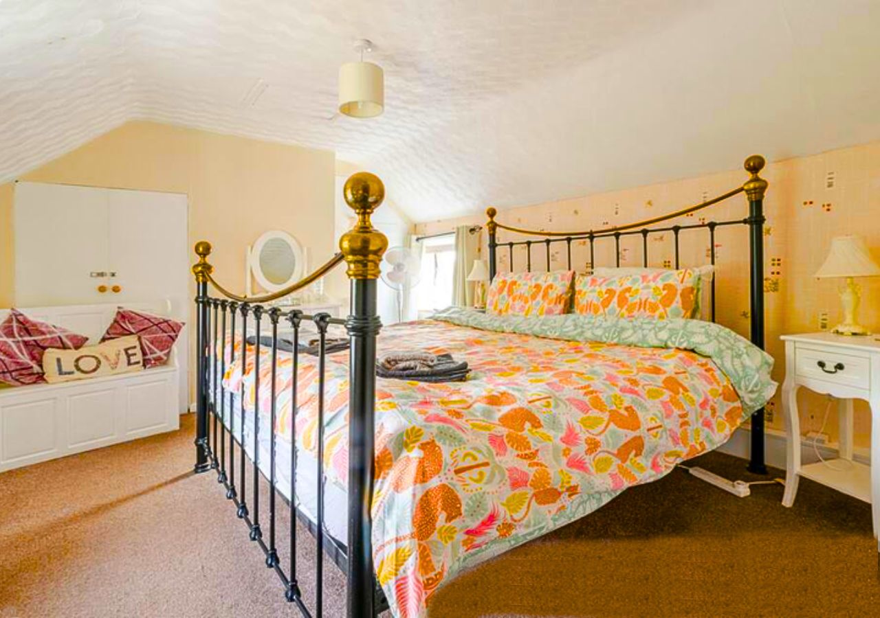 A bedroom with a bed, a bedside table, a wardrobe, and a ceiling fan.