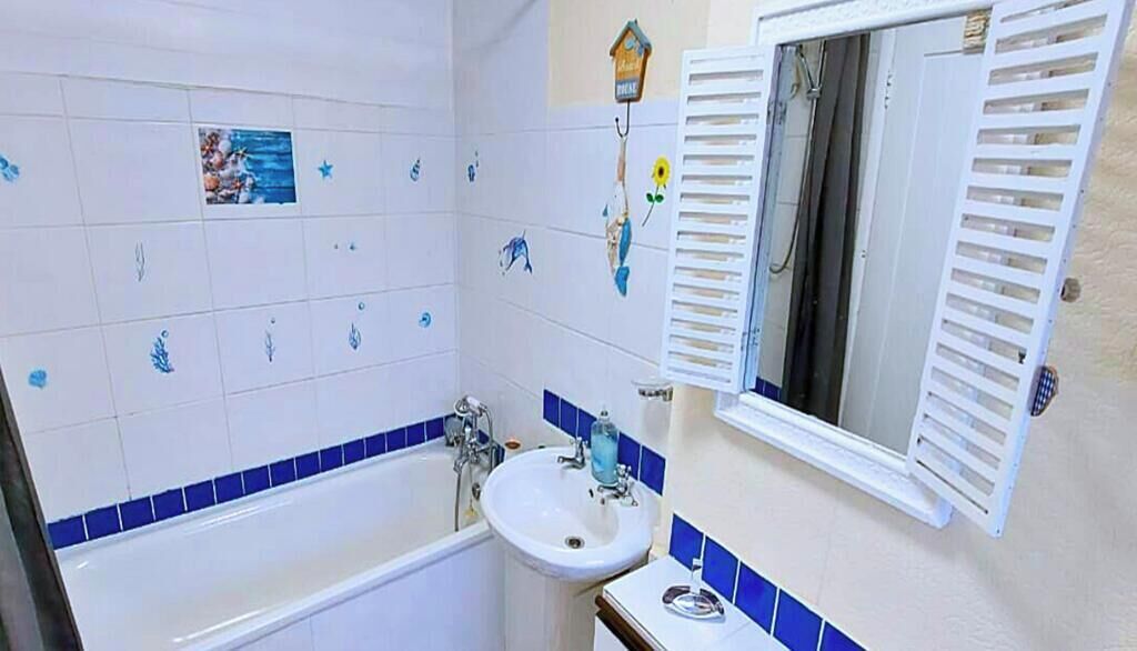 Ein Badezimmer mit einer Badewanne, einem Waschbecken und einem Spiegel mit Rollläden.
