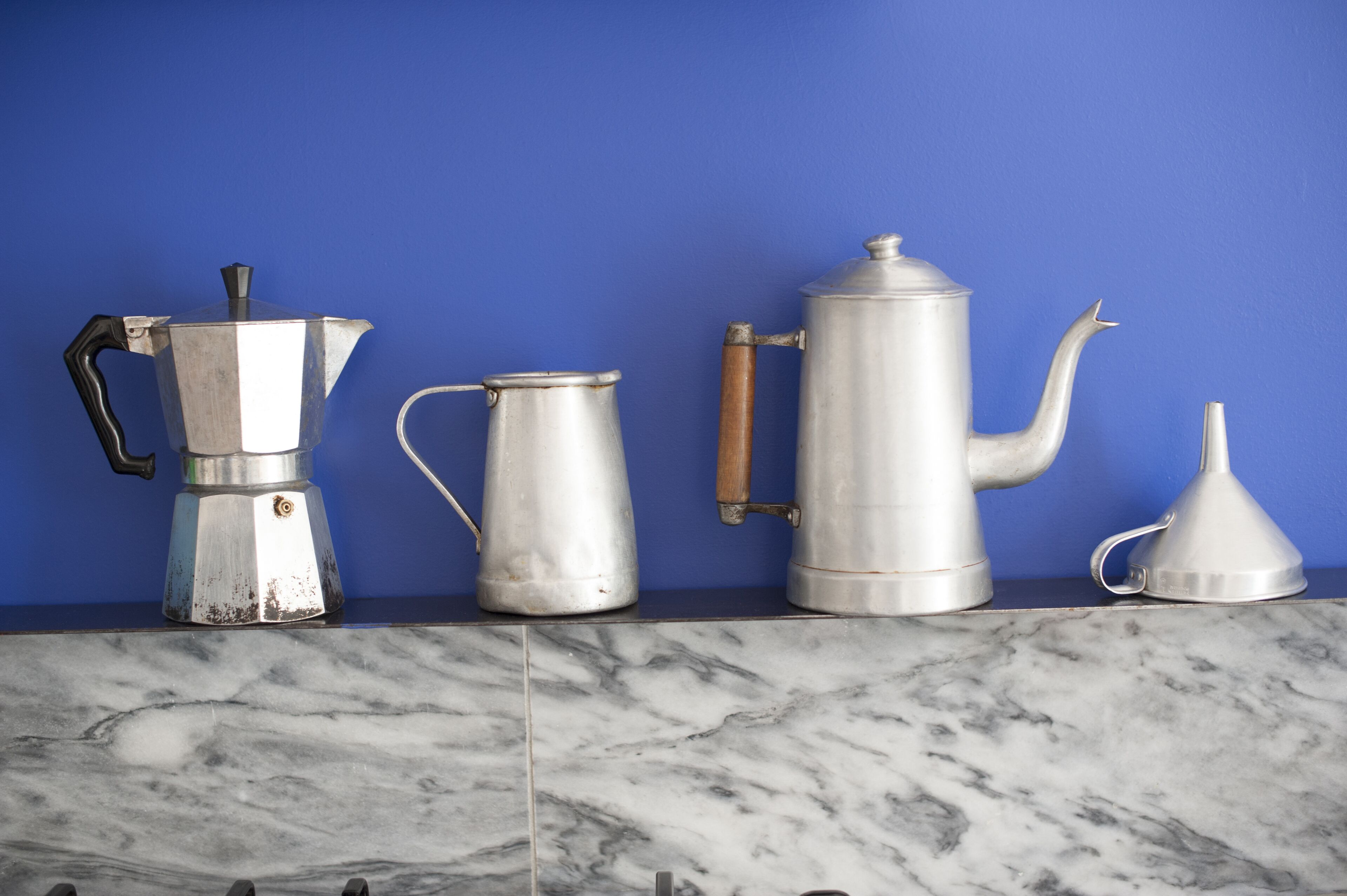 A kitchen counter with a coffee maker, a milk frother, and a coffee pot.