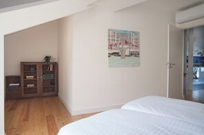 Um quarto com um armário de madeira, um quadro e uma porta que dá para a cozinha.