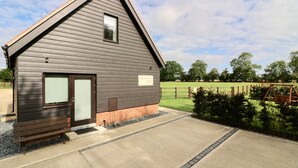 A building with a sloped roof, a door, and a bench outside. - High quality barn conversion near Cambridge to enjoy countryside & city (Cambridge)