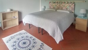 Un dormitorio con cama, mesita de noche, estante, alfombra estampada y ventilador de techo.