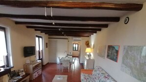 Una sala de estar con televisor, sofá y comedor.