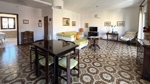 A spacious living room with a dining area, patterned floor, and a television. - Archimedes Lounge in Cefalù (Cefalù)