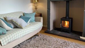 Una sala de estar acogedora con un sofá, una lámpara y una chimenea de leña.