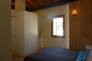 A bedroom with a bed, a wardrobe, a window, and a wooden wall. - Kaletheia house - restored mill (Volpago del Montello (TV))