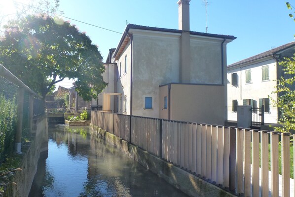 A narrow canal with a wooden fence on one side and buildings on the other. - Kaletheia house - restored mill (Volpago del Montello (TV))